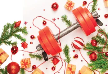 A weight is pictured alongside holiday trimmings such as garland, gifts, and Christmas tree ornaments.