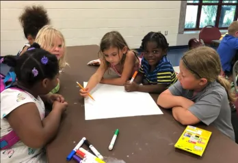 A group of children work together on an art project in a child care program at the Northeast YMCA.