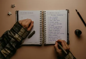 An open notebook on a table contains a list of New Year's Resolutions.