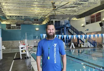 Swim instructor and lifeguard Philip smiles for a photo in the Aquatics Center at the Bear Levin Studer Y.