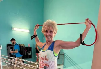 Linda smiles for a photo as she works out near the stairs on the wellness floor at the Bear Levin Studer Y.