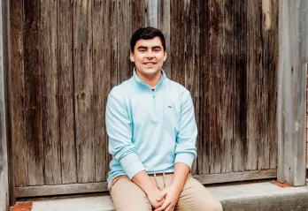 Jackson smiles for a photo set against a backdrop of weathered wood and concrete.