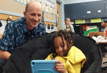 man helps student read on a tablet