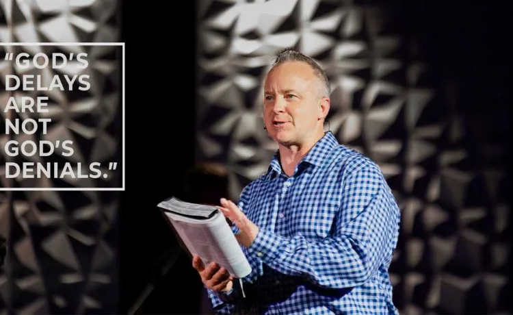 A pastor holds a Bible while speaking to a group.