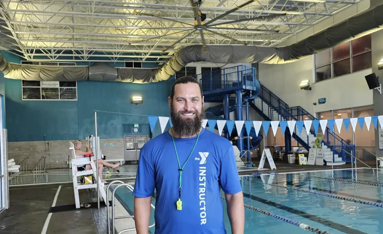 Swim instructor and lifeguard Philip smiles for a photo in the Aquatics Center at the Bear Levin Studer Y.