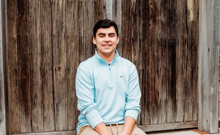 Jackson smiles for a photo set against a backdrop of weathered wood and concrete.
