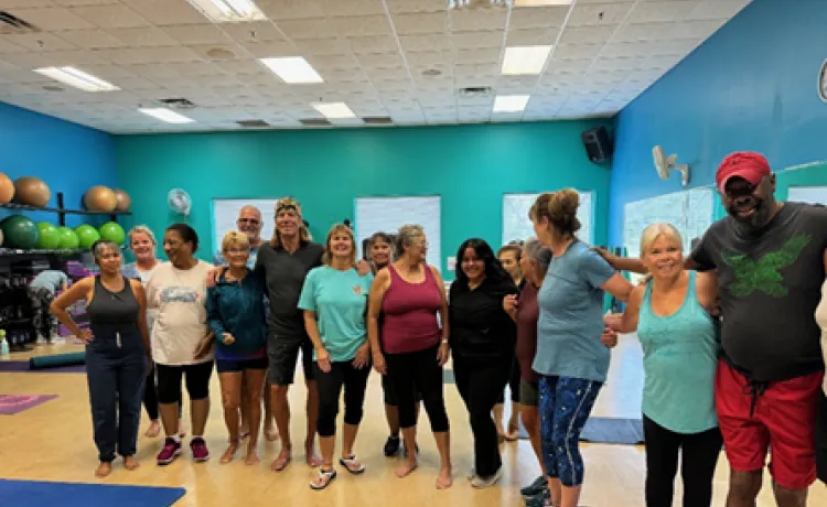 A group who have been attending group exercise together gather around and smile for a photo at the Pullum Y.