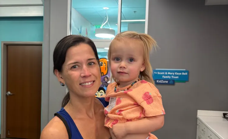 Bear Levin Studer YMCA member Ashley is pictured in the lobby of the branch with the KidZone visible behind her as she holds her daughter Breaia.