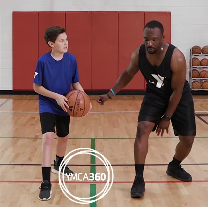 Y coach and teen playing basketball