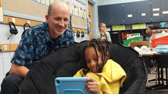 man helps student read on a tablet