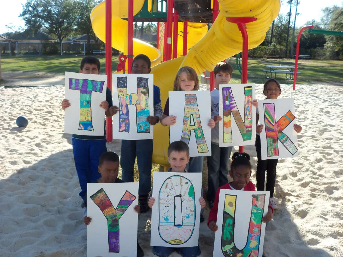 children hold up thank you sign