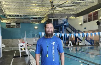 Swim instructor and lifeguard Philip smiles for a photo in the Aquatics Center at the Bear Levin Studer Y.