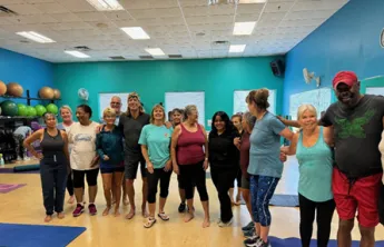 A group who have been attending group exercise together gather around and smile for a photo at the Pullum Y.