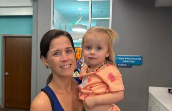 Bear Levin Studer YMCA member Ashley is pictured in the lobby of the branch with the KidZone visible behind her as she holds her daughter Breaia.